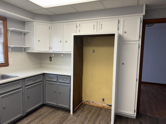 kitchen featuring gray cabinets, dark wood finished floors, white cabinets, light countertops, and decorative backsplash