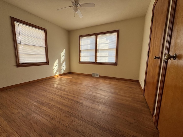 unfurnished bedroom with wood finished floors, visible vents, a closet, and baseboards