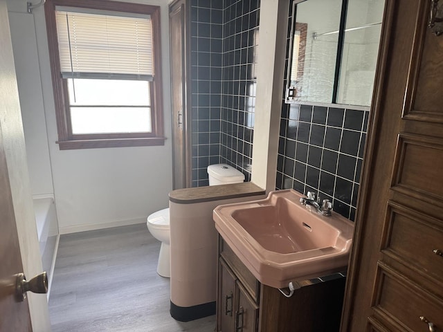 bathroom with tile walls, baseboards, toilet, wood finished floors, and vanity