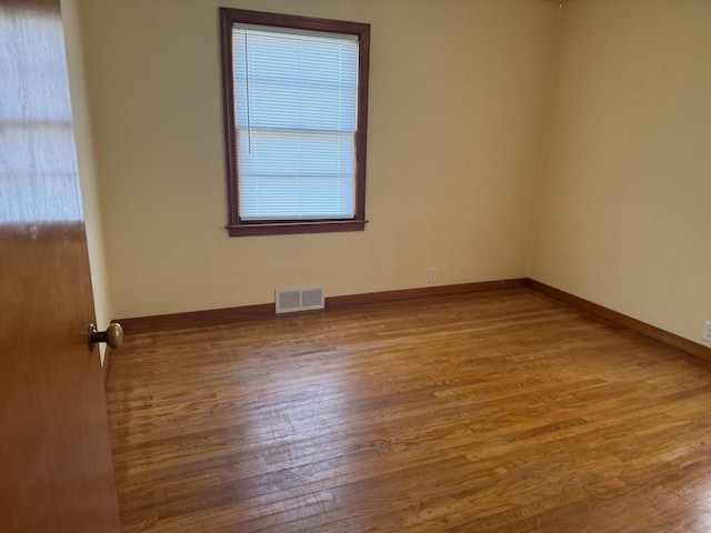 unfurnished room with visible vents, baseboards, and wood finished floors