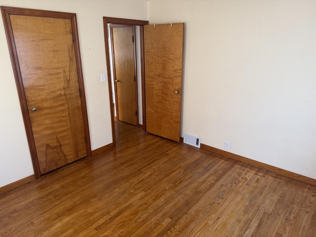 unfurnished bedroom featuring visible vents, baseboards, and wood finished floors