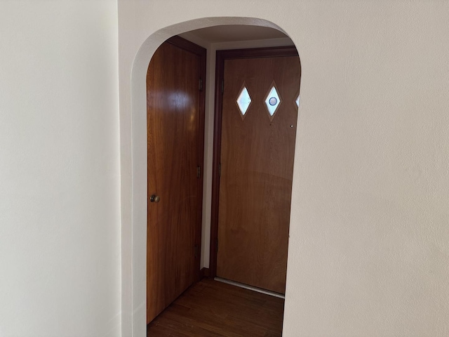 hall with dark wood-type flooring and arched walkways