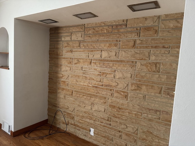 interior space featuring arched walkways, visible vents, baseboards, and wood finished floors