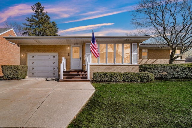 view of front of home with driveway, brick siding, an attached garage, and a front yard