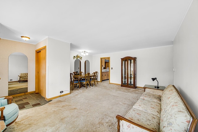 living room featuring arched walkways, carpet, baseboards, and ornamental molding