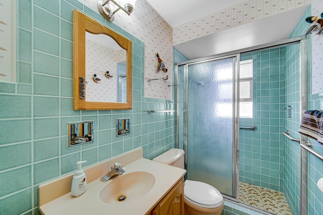 bathroom with vanity, toilet, tile walls, and a shower stall