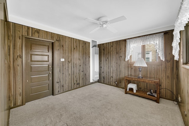 interior space with carpet, ceiling fan, and wooden walls