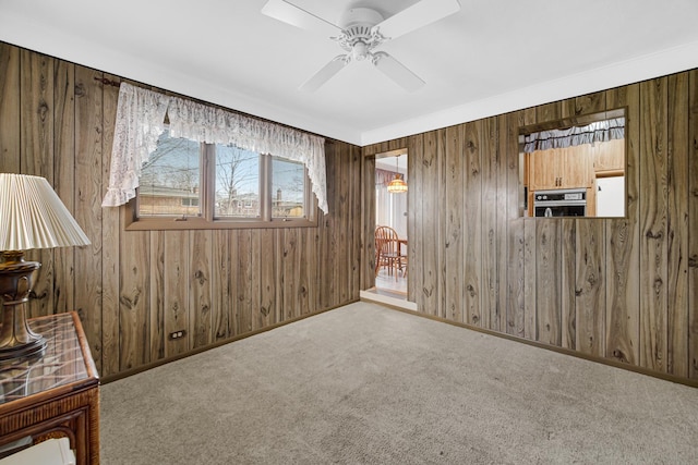 interior space with baseboards, ceiling fan, and wood walls