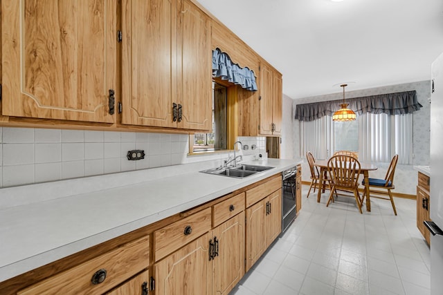 kitchen with a sink, decorative light fixtures, wallpapered walls, black dishwasher, and light countertops