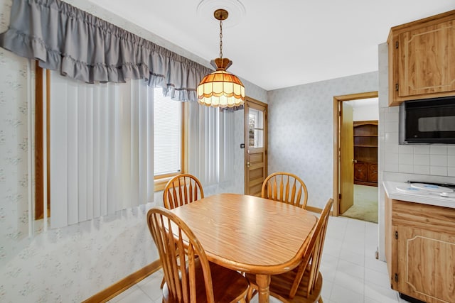 dining room featuring light tile patterned floors, baseboards, and wallpapered walls