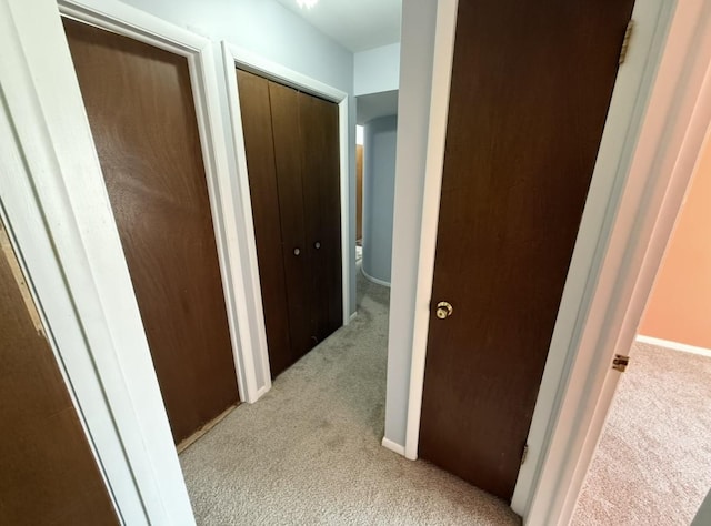 hall featuring light colored carpet and baseboards