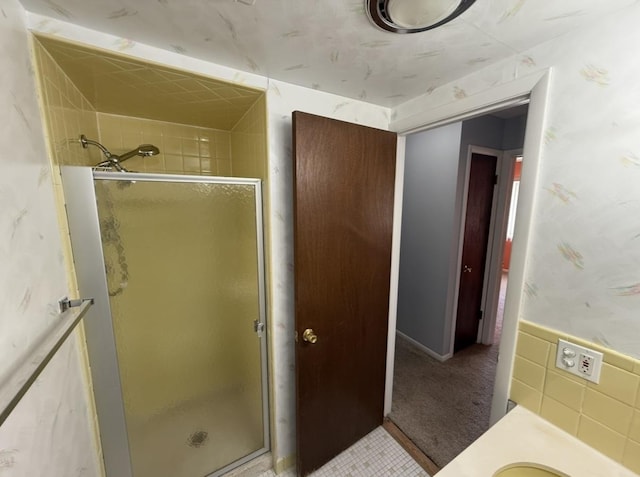 bathroom with a shower stall and tile walls