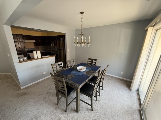 dining space with a chandelier, light carpet, and baseboards