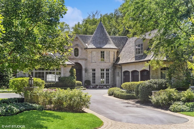 french country home with aphalt driveway and stone siding