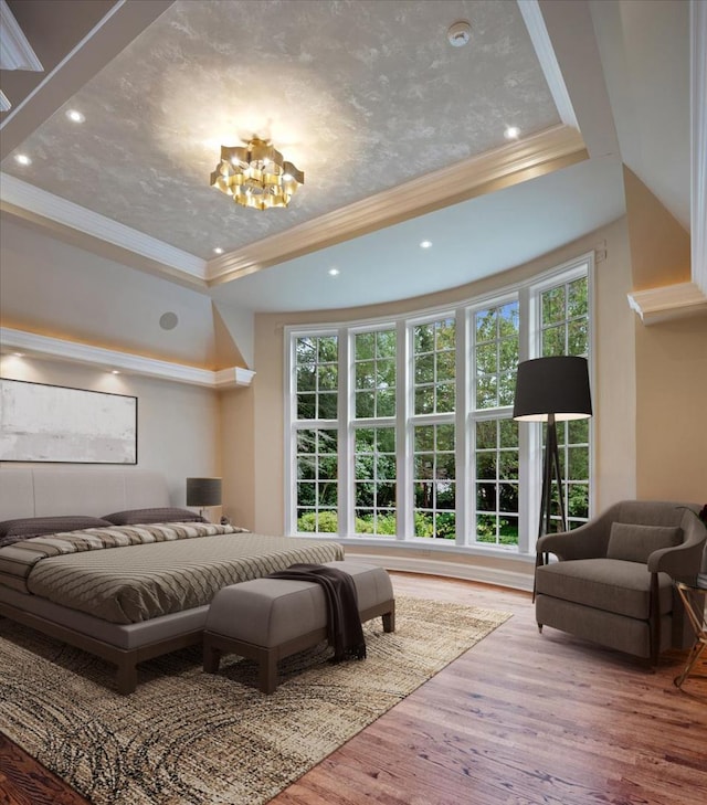 bedroom with crown molding, a raised ceiling, an inviting chandelier, and wood finished floors