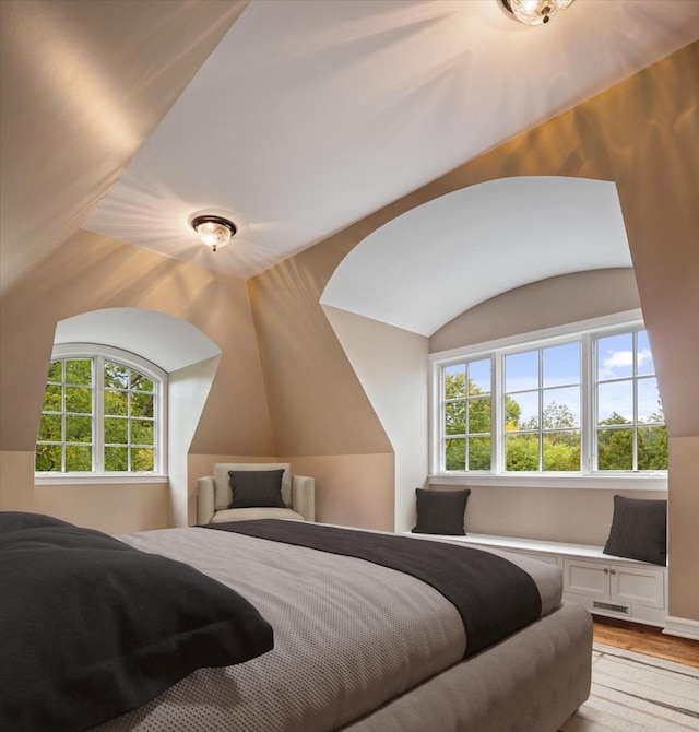 bedroom with visible vents, multiple windows, lofted ceiling, and light wood-style floors