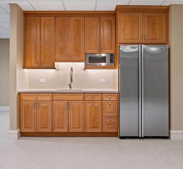 kitchen featuring a sink, stainless steel appliances, brown cabinets, and light countertops