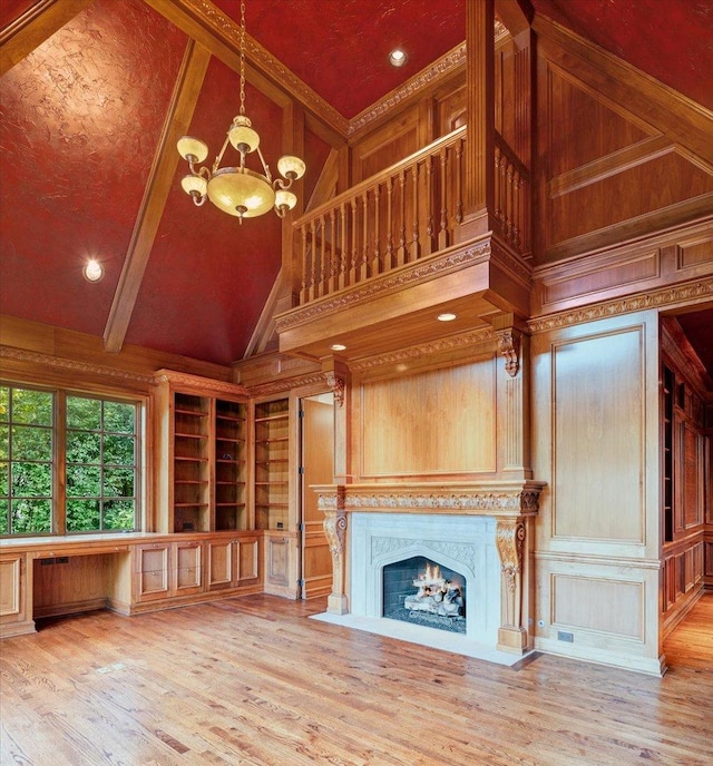 unfurnished living room with a chandelier, built in features, high vaulted ceiling, and wood-type flooring