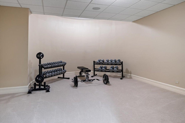 exercise room with a paneled ceiling, baseboards, and carpet