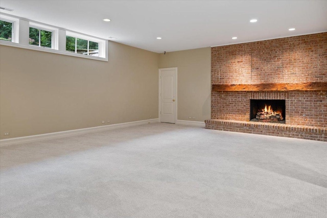 unfurnished living room with recessed lighting, baseboards, light carpet, and a fireplace