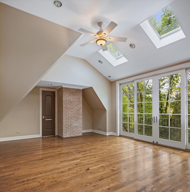 bonus room with visible vents, baseboards, vaulted ceiling with skylight, wood finished floors, and a ceiling fan