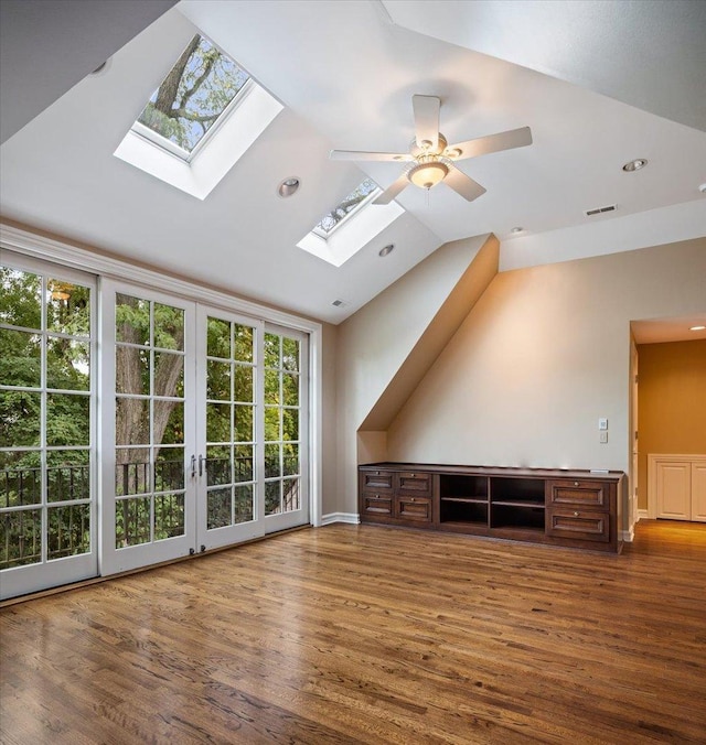 additional living space featuring lofted ceiling with skylight, wood finished floors, visible vents, and ceiling fan