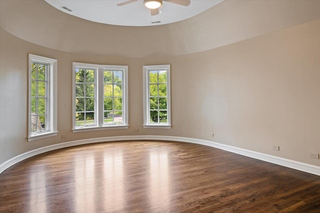 unfurnished room featuring dark wood-style floors, visible vents, ceiling fan, and baseboards