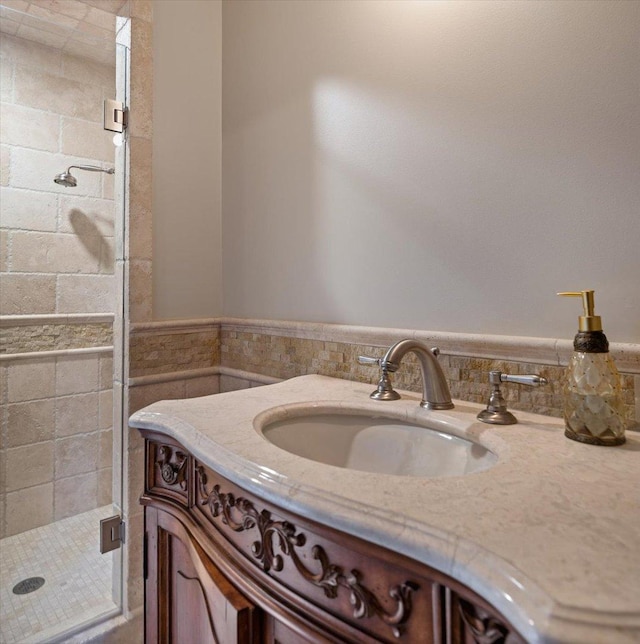 full bathroom featuring vanity, a wainscoted wall, and a stall shower