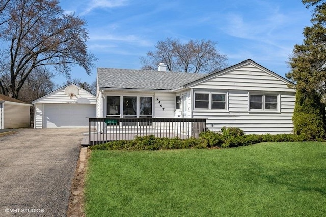 ranch-style house with an outbuilding, a front yard, a chimney, a shingled roof, and a detached garage