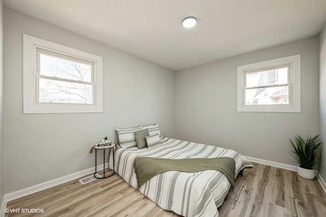 bedroom featuring light wood-style flooring, visible vents, and baseboards