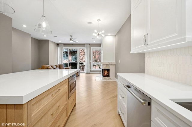 kitchen featuring tasteful backsplash, open floor plan, light countertops, appliances with stainless steel finishes, and light wood-style floors