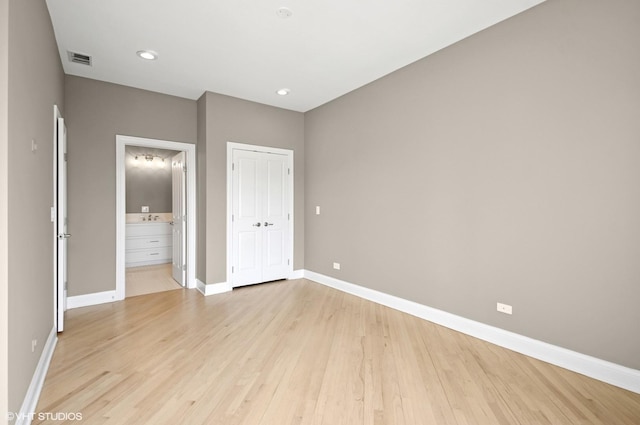 unfurnished bedroom with visible vents, ensuite bath, a closet, light wood finished floors, and baseboards