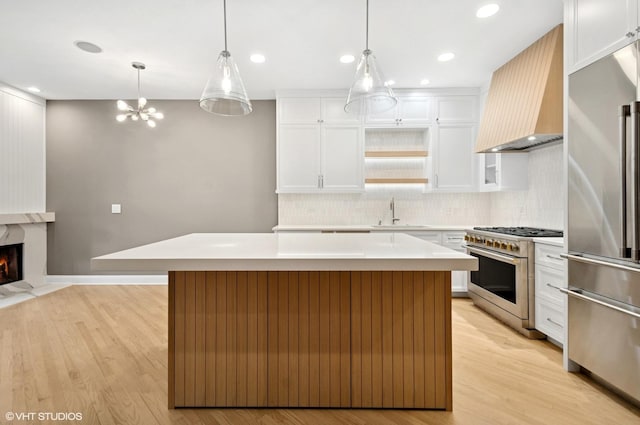 kitchen featuring premium range hood, premium appliances, a center island, light wood-style floors, and light countertops