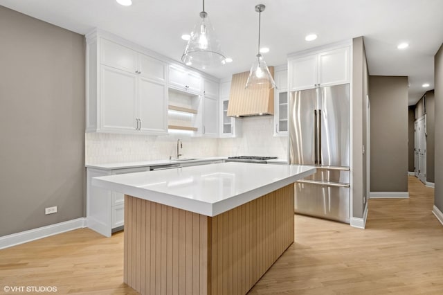 kitchen featuring premium range hood, a center island, light wood-style floors, appliances with stainless steel finishes, and light countertops