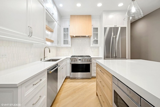 kitchen featuring high quality appliances, custom range hood, a sink, light wood-style floors, and light countertops