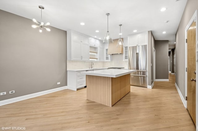 kitchen featuring custom exhaust hood, high quality fridge, light wood-style floors, and a center island