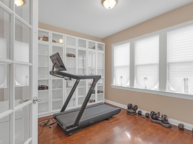 workout area featuring french doors, baseboards, and wood finished floors