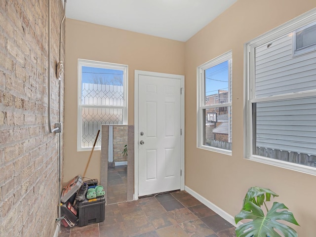 entrance foyer featuring baseboards and stone finish floor