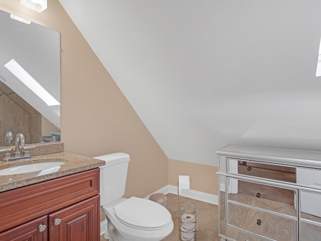 bathroom with lofted ceiling with skylight, toilet, tile patterned flooring, baseboards, and vanity