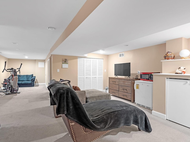 bedroom featuring fridge, light colored carpet, visible vents, and baseboards