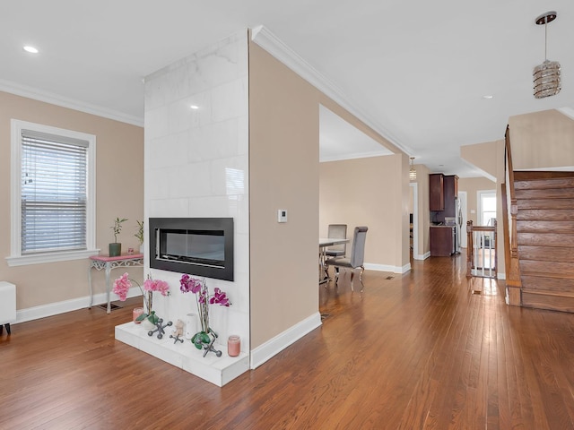 living area featuring a healthy amount of sunlight, dark wood-type flooring, and ornamental molding