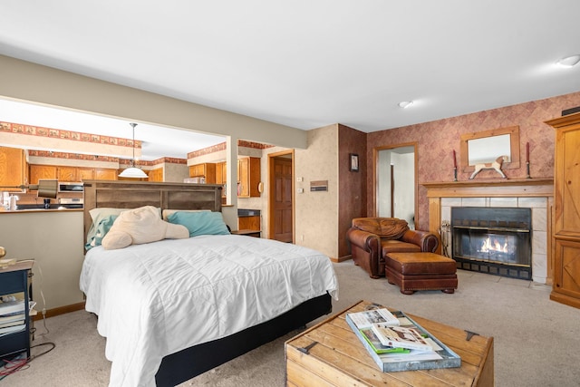 bedroom with baseboards, light carpet, a tiled fireplace, and wallpapered walls