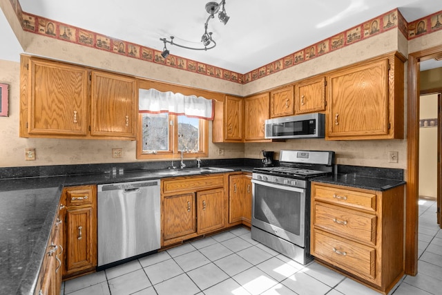 kitchen with light tile patterned flooring, brown cabinetry, appliances with stainless steel finishes, and a sink