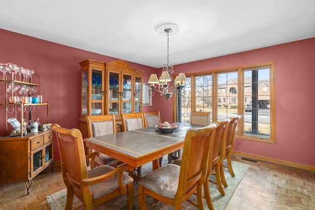 dining area with a notable chandelier, visible vents, and baseboards