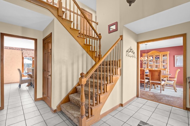 staircase featuring an inviting chandelier, tile patterned floors, and baseboards