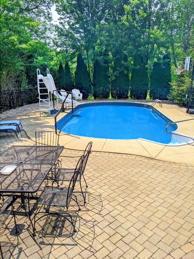 view of swimming pool featuring a patio area, outdoor dining space, a fenced in pool, and fence