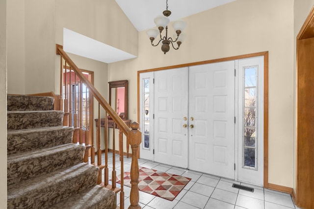 foyer with stairway, visible vents, high vaulted ceiling, an inviting chandelier, and light tile patterned flooring