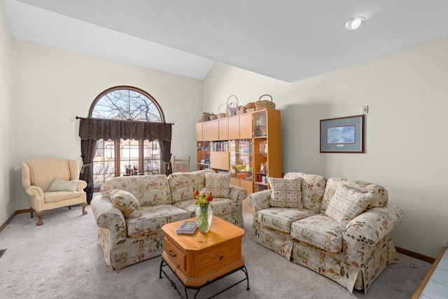 carpeted living area featuring lofted ceiling and baseboards