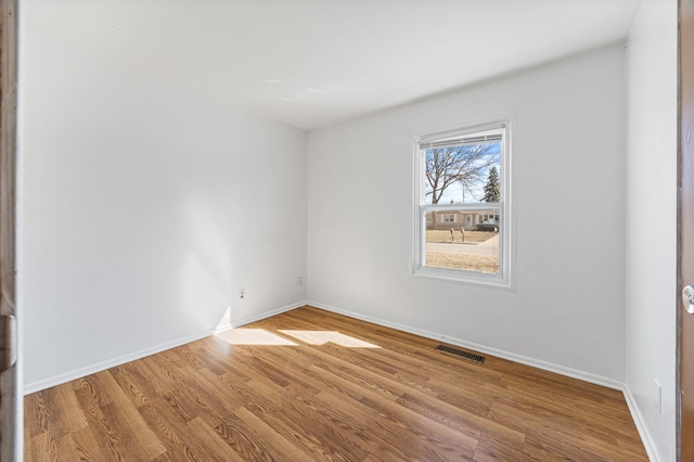 spare room featuring visible vents, baseboards, and wood finished floors