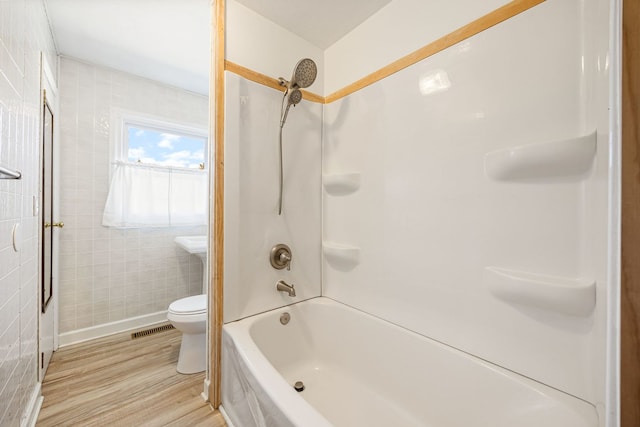 bathroom with visible vents, toilet, tile walls, and wood finished floors